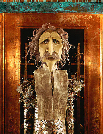 The Gardener puppet has long scraggly light hair and bushy mustache framed in copper