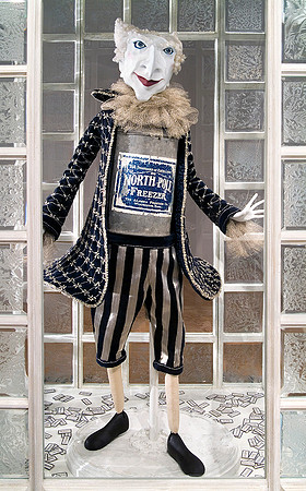 The Snowshoe Salesman puppet dressed in blue and silver stripped pants, torso made from an antique ice cream canister, standing in